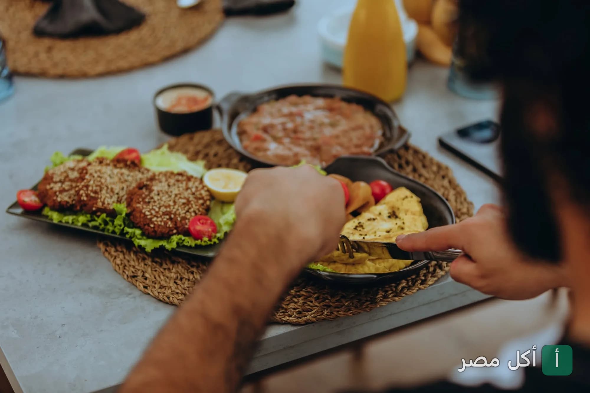 شخص يتناول وجبة إفطار متنوعة تضم أطباقاً جانبية في مطعم إيزويا بالإسكندرية.