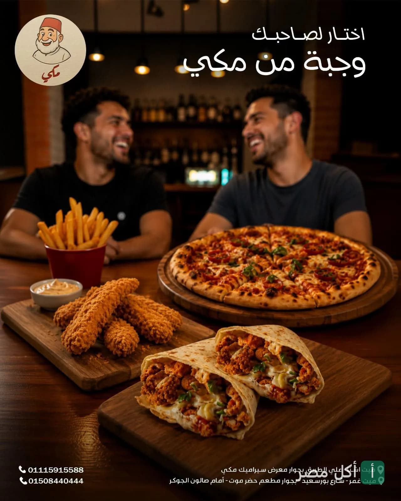 شابان يضحكان أمام طاولة عليها بيتزا، دجاج مقلي، وساندوتشات في مطعم مكي بالمنشية.