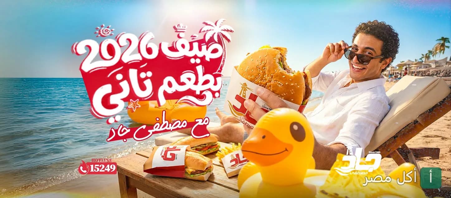 إعلان صيفي لمطعم مصطفى جاد فرع الاتحاد بالإسكندرية يظهر شاباً يتناول شطيرة على الشاطئ.