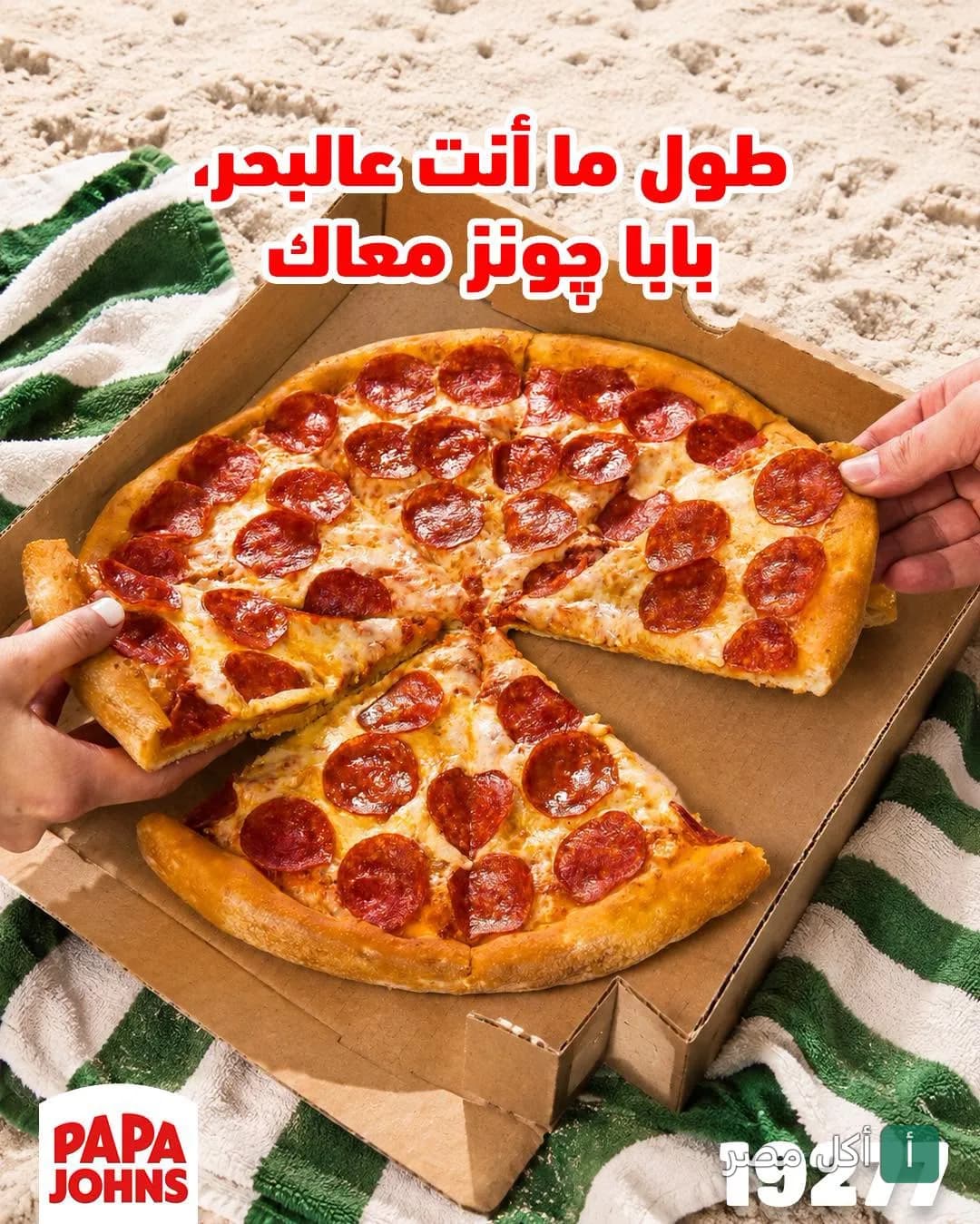 بيتزا بيبيروني من بابا جونز في علبة كرتون على رمال الشاطئ.