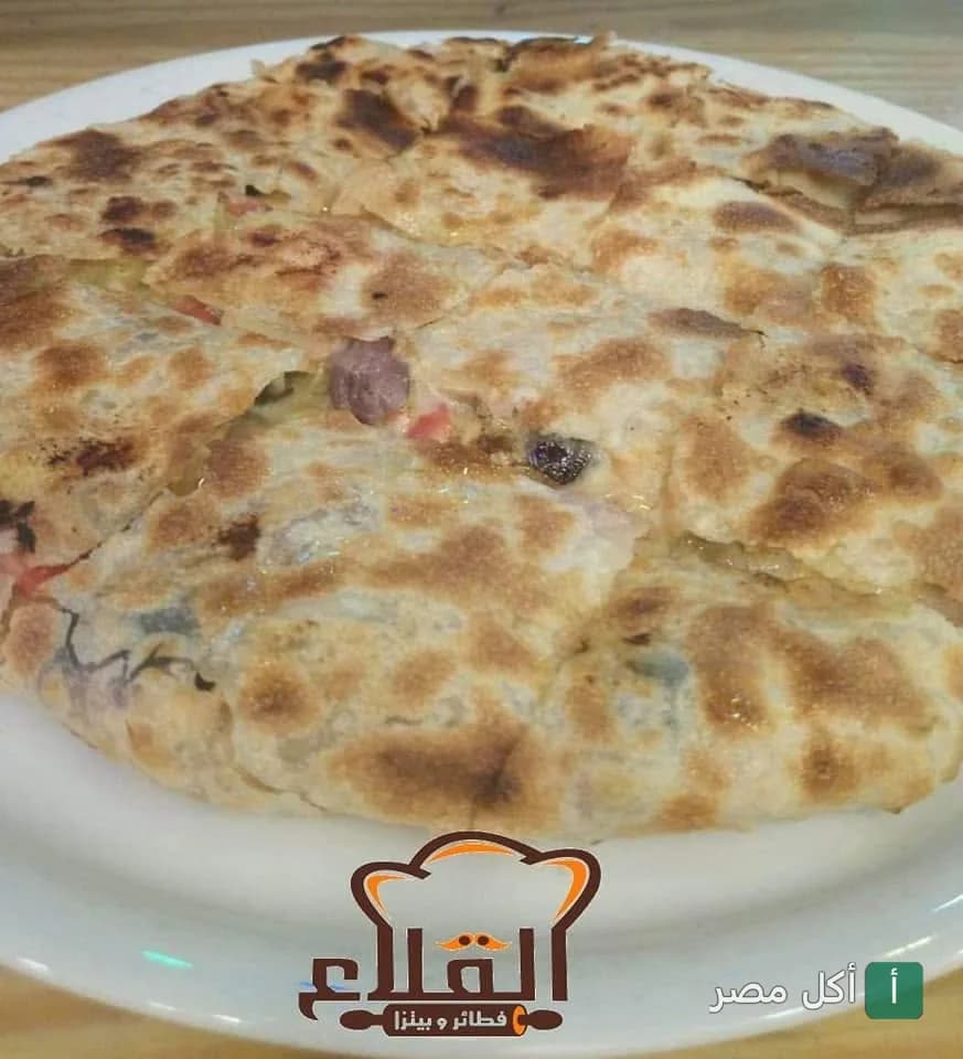 فطيرة شرقية محمرة ومقطعة في طبق أبيض من مطعم فطير القلاع سموحة بالإسكندرية.