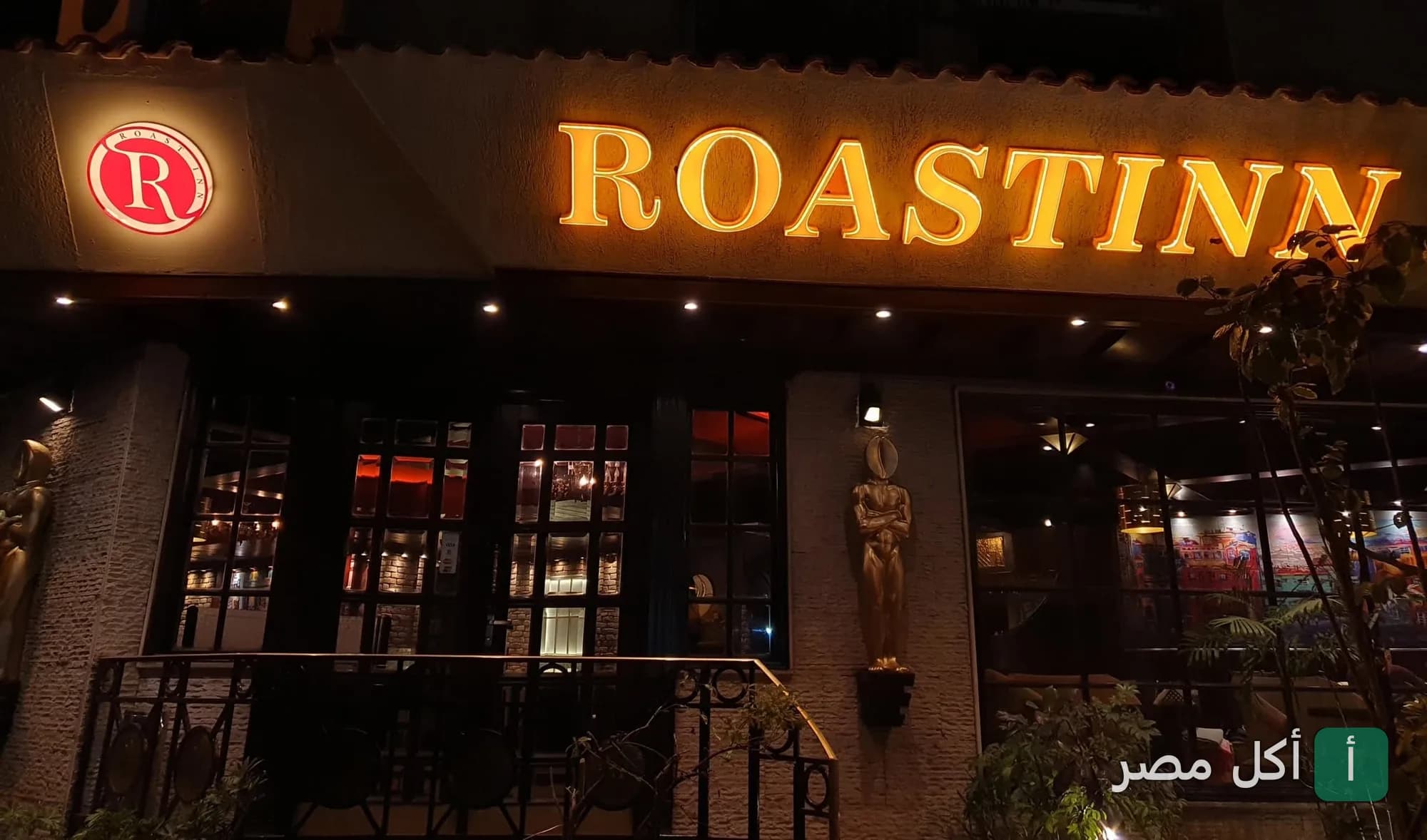 واجهة مطعم وكافيه تريو آر في سيدي بشر بالإسكندرية ليلاً مع لافتة مضيئة باسم Roastinn.