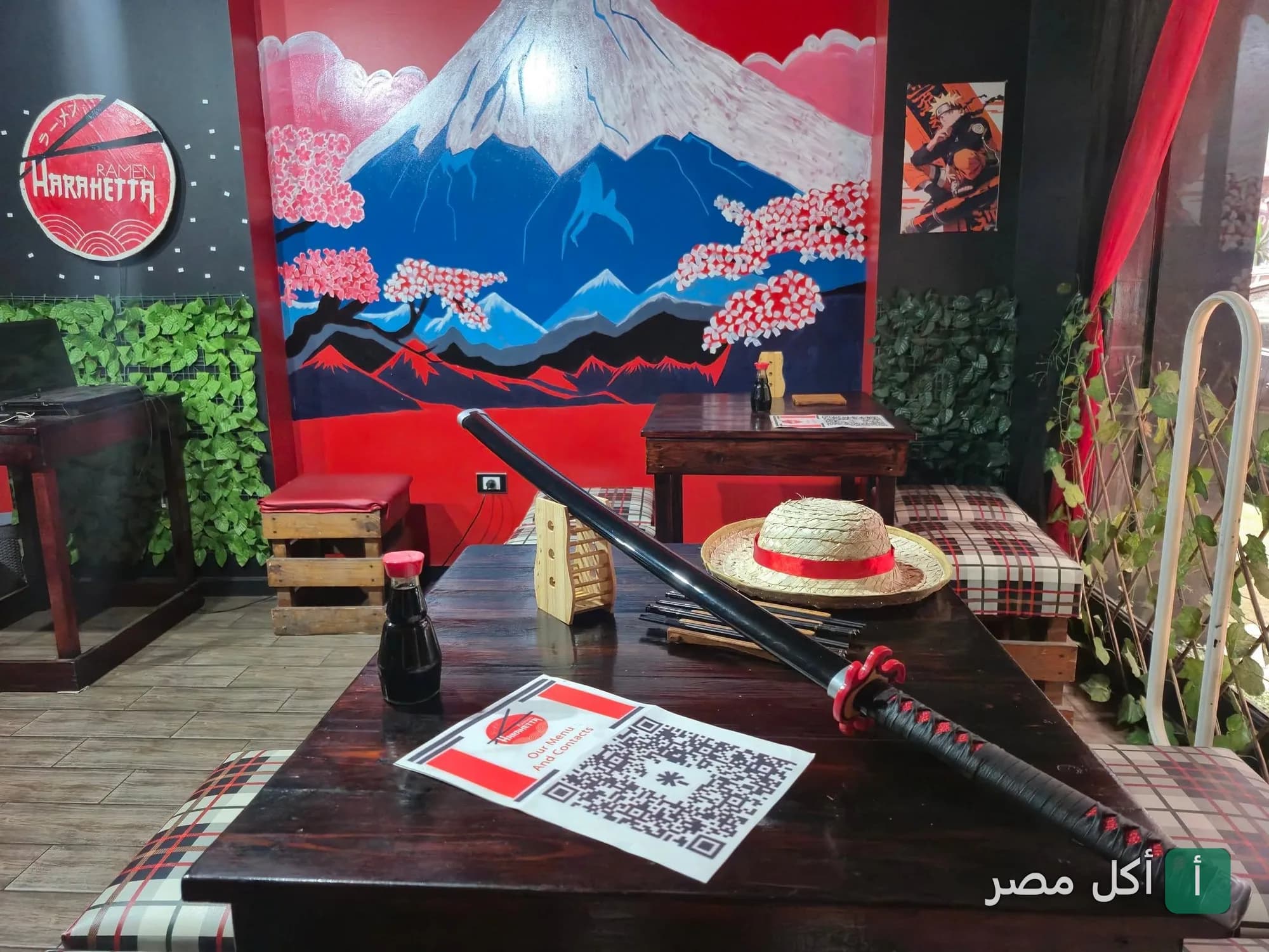 ديكور ياباني مستوحى من الأنمي داخل مطعم هراهيتا رامن في الإسكندرية مع لوحة جبل فوجي وكاتانا على الطاولة.