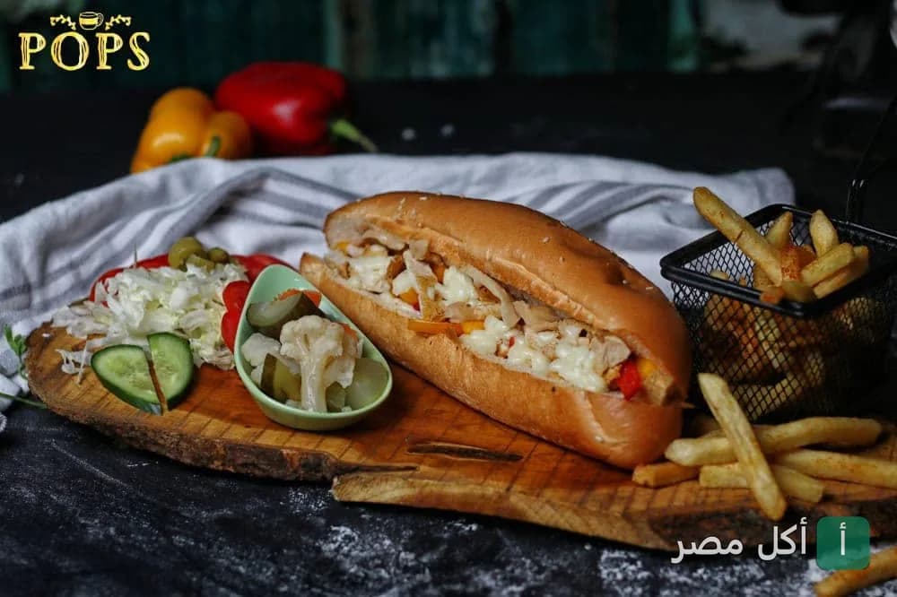 ساندوتش دجاج مع بطاطس مقلية ومخلل على لوح خشبي في بوبس كافيه بسيدي بشر، الإسكندرية.