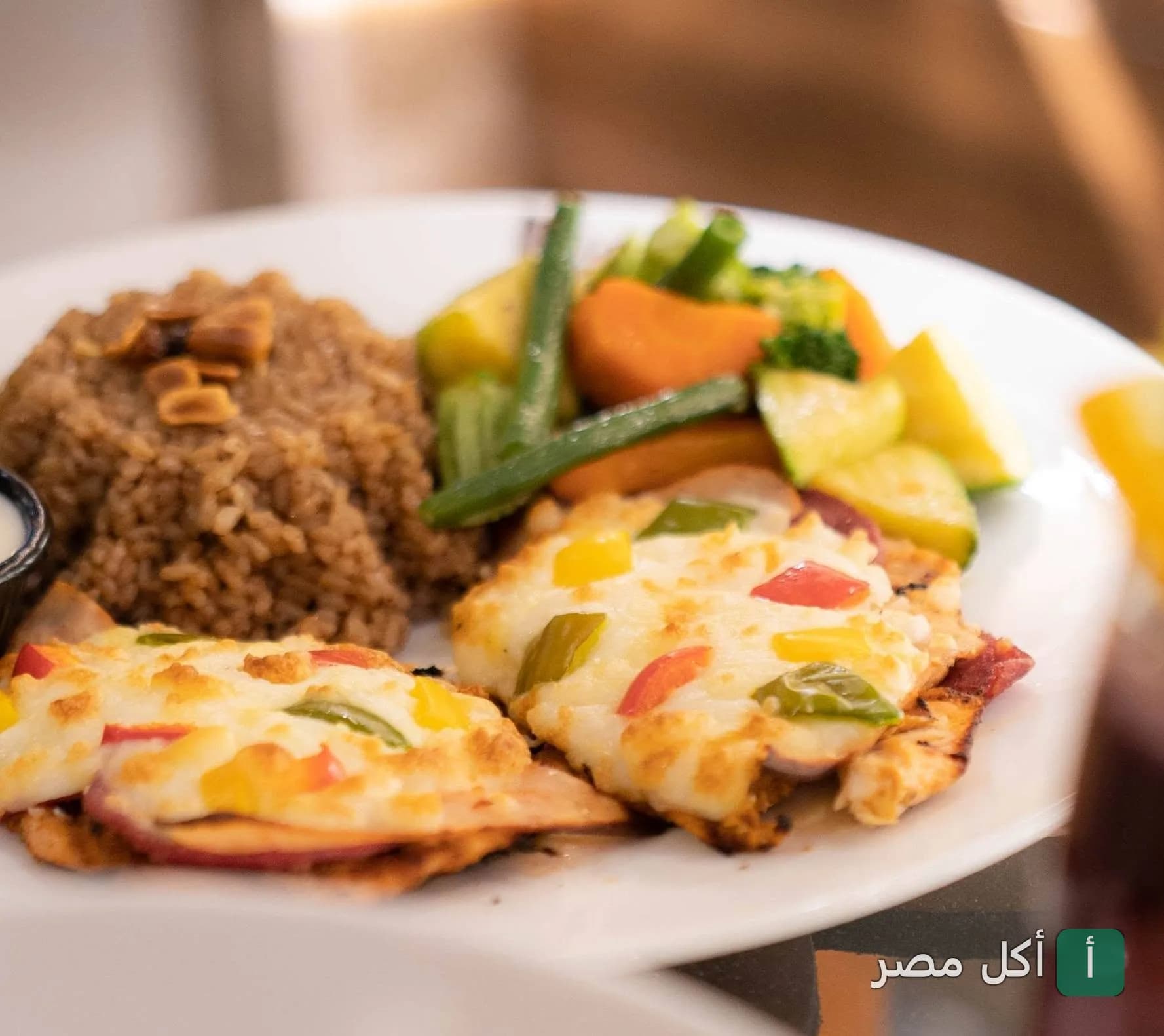 طبق دجاج مشوي مغطى بالجبنة والخضروات مع أرز بني وخضار سوتيه في مطعم مورانو بالإسكندرية.