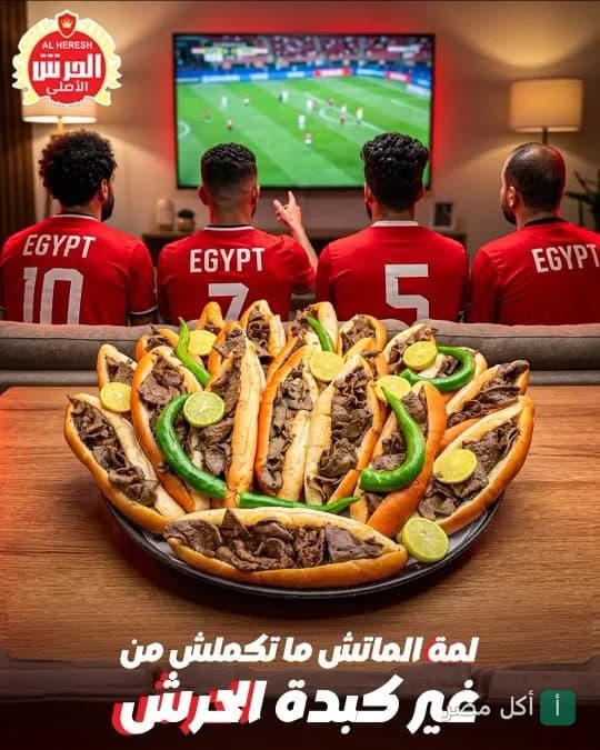 طبق كبير من سندوتشات كبدة الحرش بالبيطاش في الإسكندرية مع أشخاص يشاهدون مباراة كرة قدم.