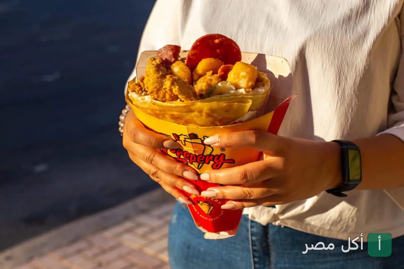 شخص يمسك كريب محشو بقطع الدجاج والبطاطس في ذا كريبري إيجيبت بسيدي جابر بالإسكندرية.