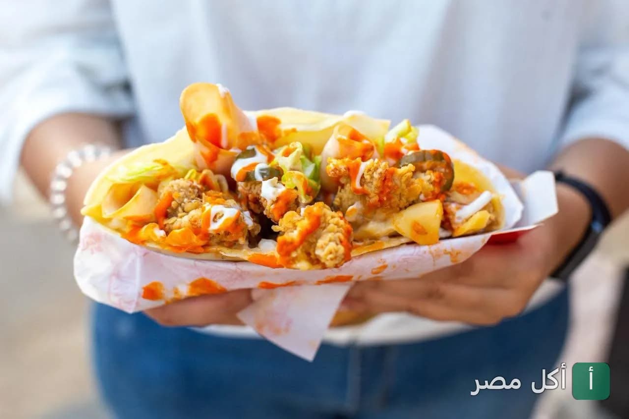 شخص يمسك ساندوتش كريب مقرمش بصوص حار من ذا كريبري إيجيبت في سيدي جابر بالإسكندرية.