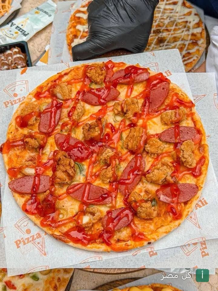 بيتزا علي في برج العرب مغطاة بقطع الدجاج والسجق مع صوص الكاتشب.
