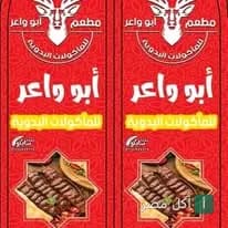 لوحة إعلانية حمراء لمطعم أبو واعر للمأكولات البدوية في برج العرب، تعرض شعار الغزال وأطباق المشويات.