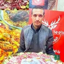 الشيف عطية المغواري أمام أطباق المأكولات البدوية والمشويات في مطعمه ببرج العرب.