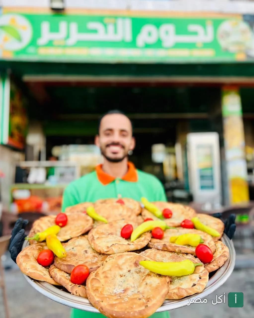 موظف في مطعم نجوم التحرير ببرج العرب يحمل صينية فطائر مزينة بقطع الطماطم والفلفل الحار.