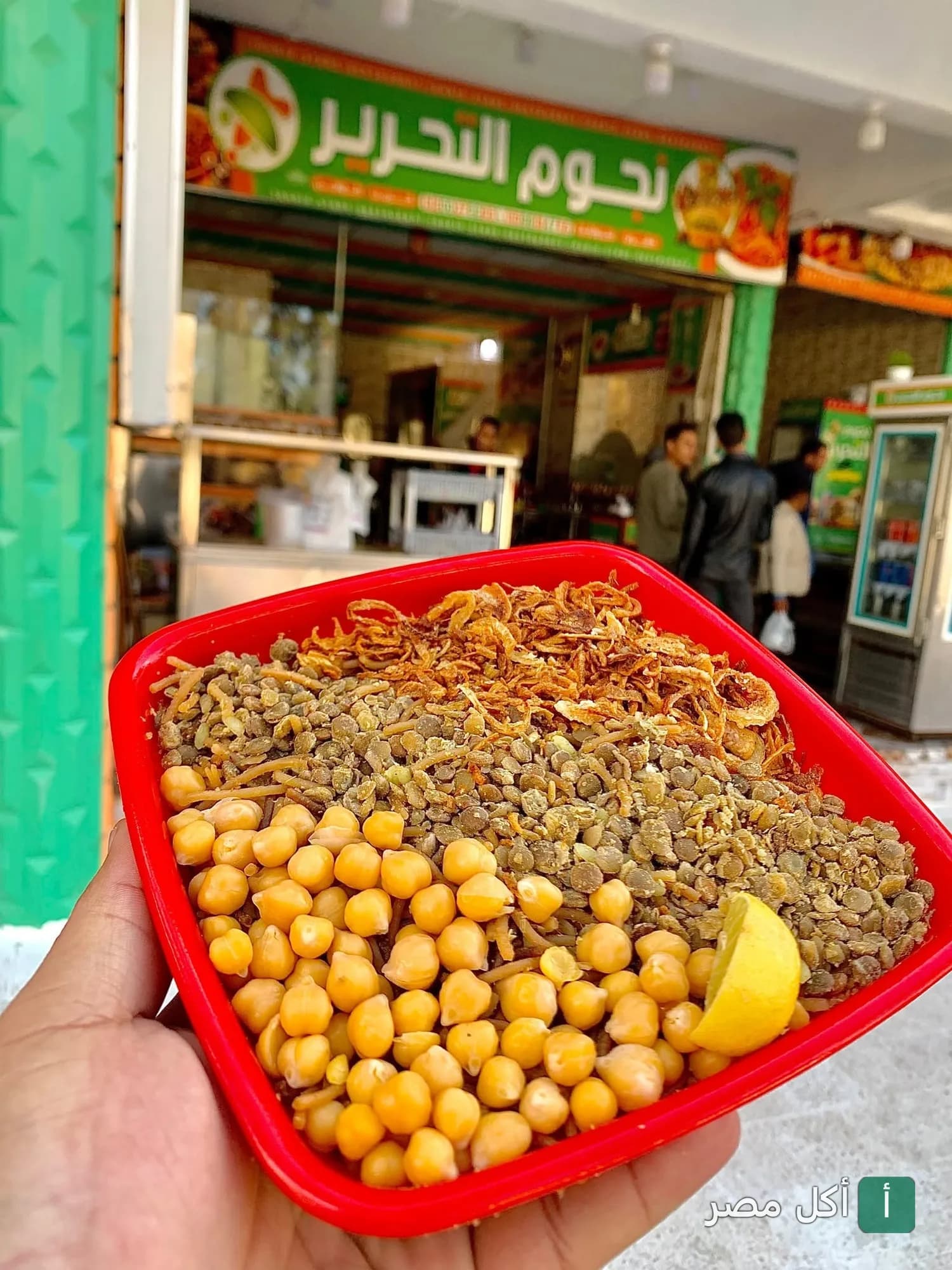 طبق كشري مصري في علبة حمراء أمام واجهة مطعم نجوم التحرير في برج العرب.