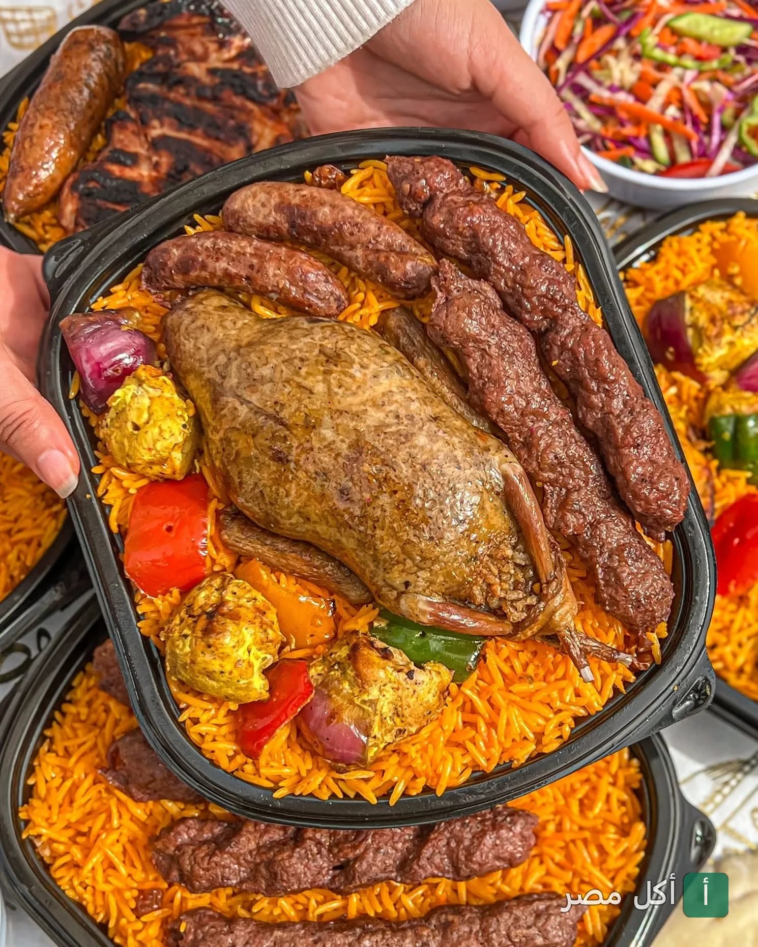 وجبة شرقية من مطعم حضرموت في كرموز، تحتوي على بط محشي، كفتة مشوية، وقطع دجاج مع أرز أصفر.