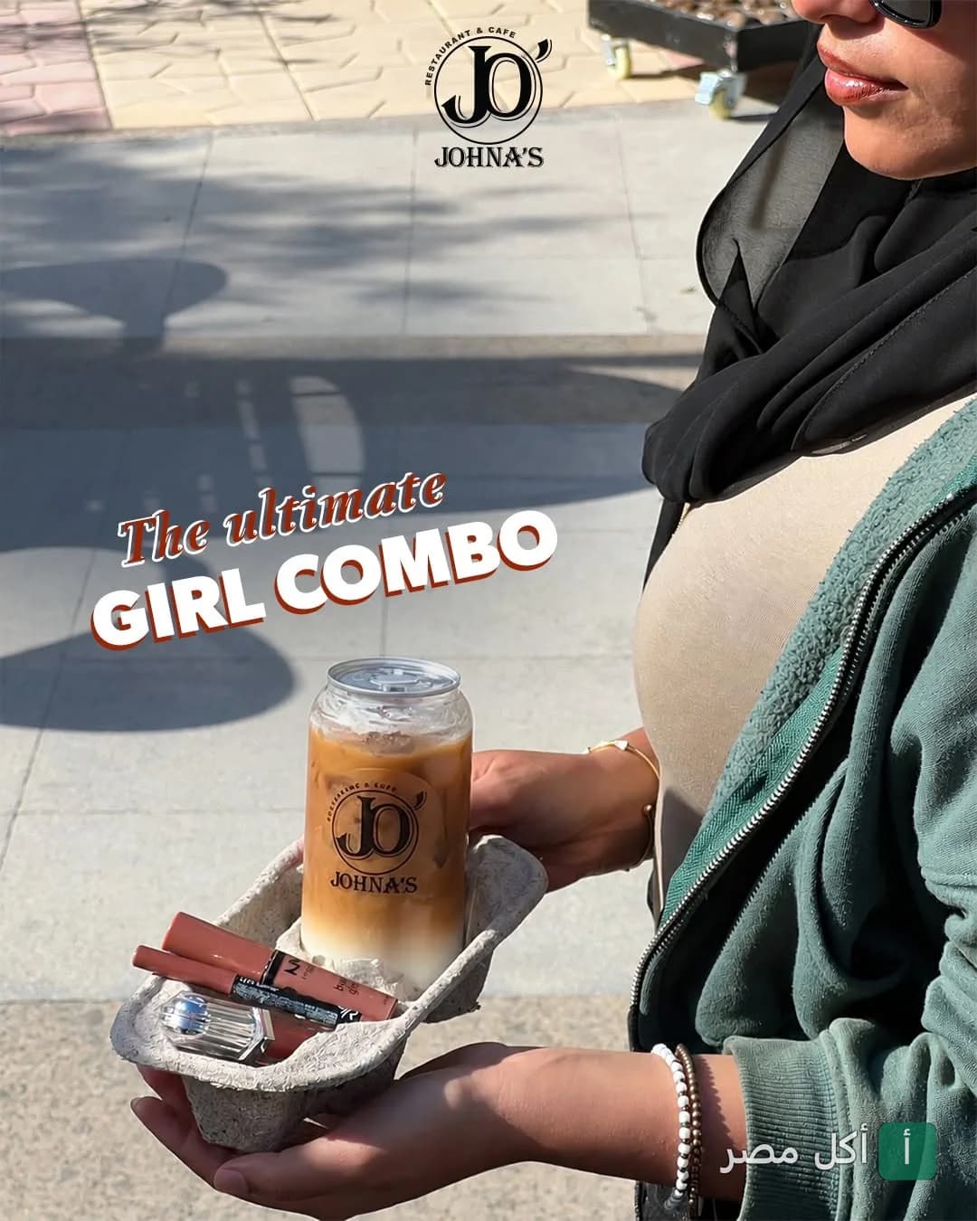 زبونة تحمل كوب قهوة مثلجة من جوناز كافيه مع مستحضرات تجميل في حامل أكواب ورقي.