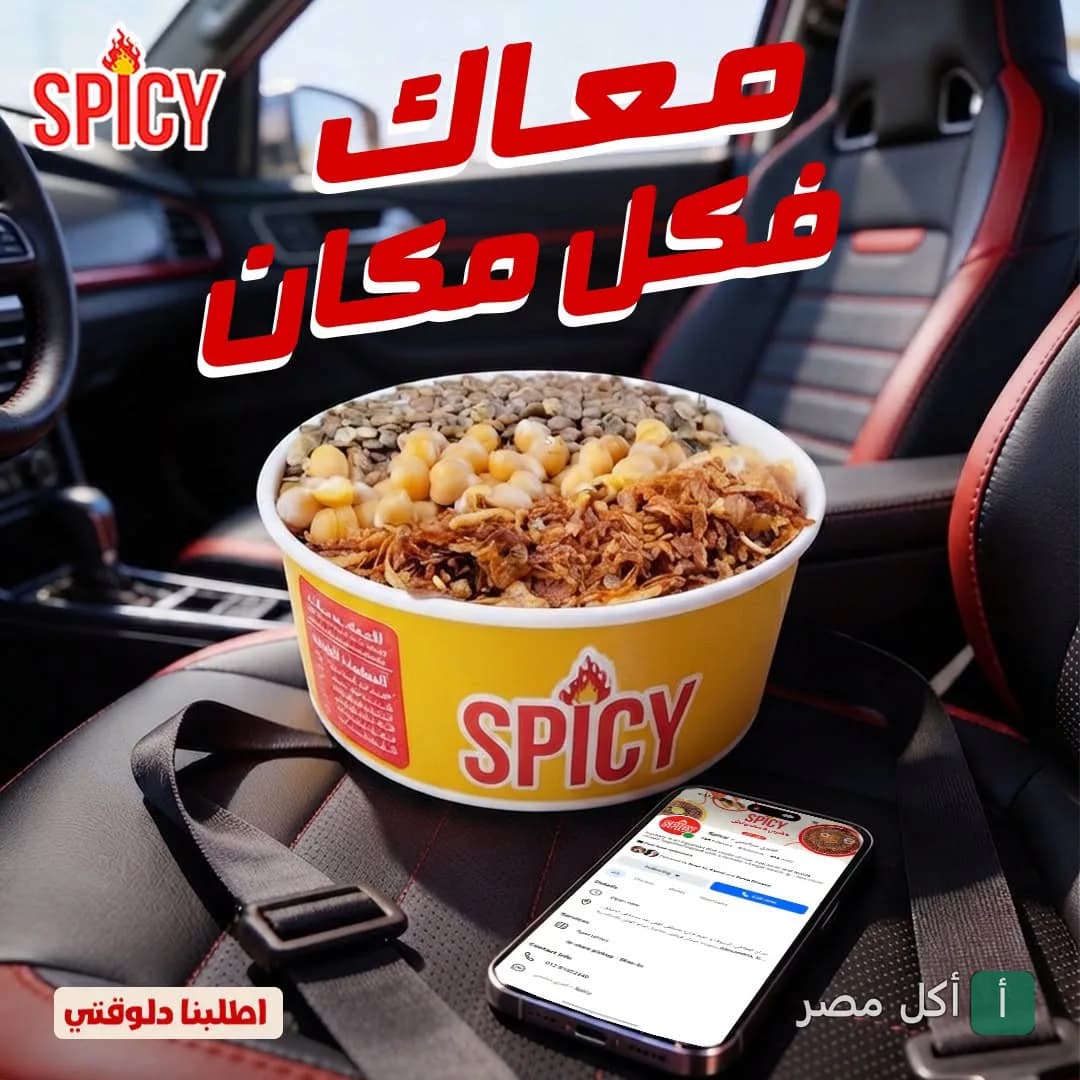 علبة كشري من مطعم سبايسي في كرموز موضوعة داخل سيارة بجانب هاتف محمول.