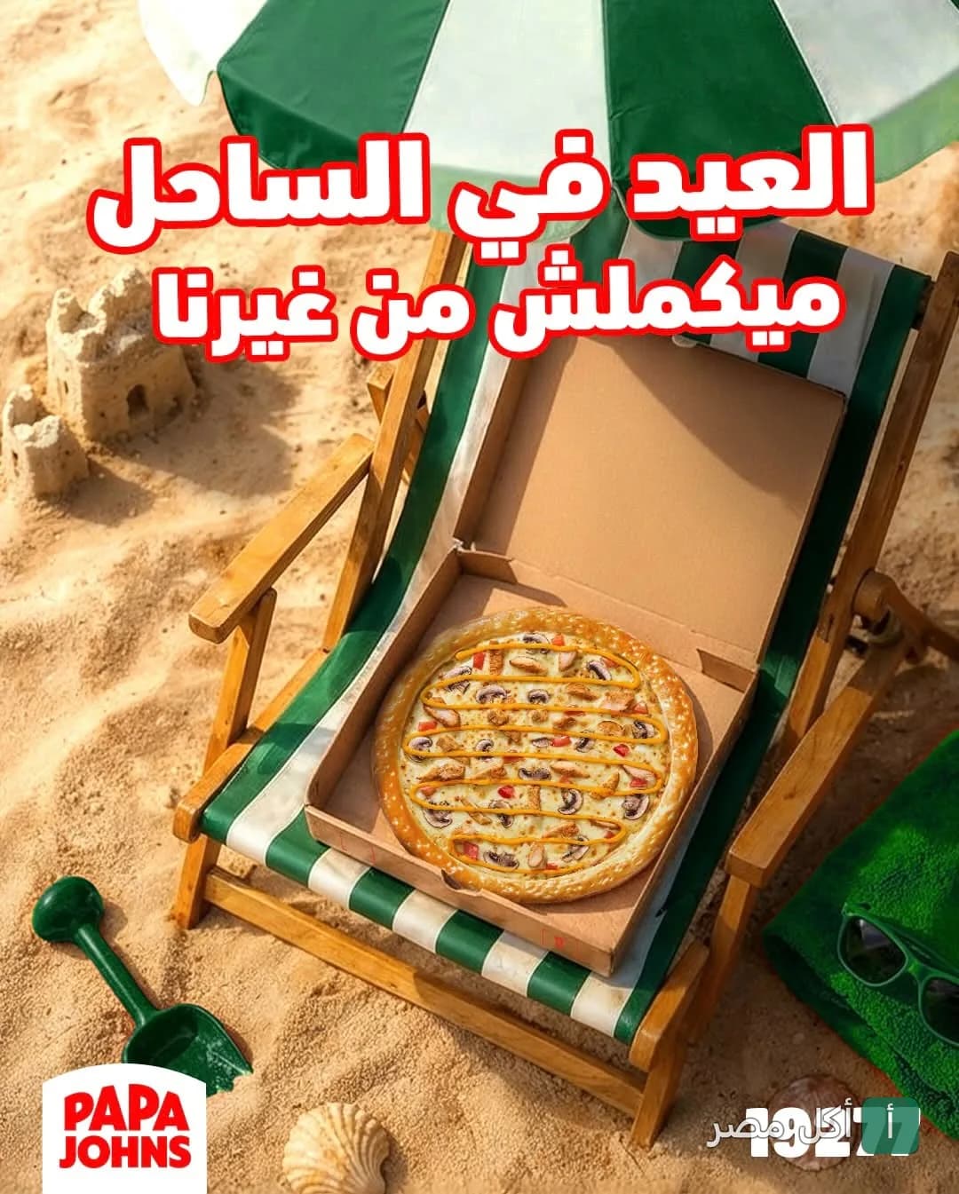 علبة بيتزا بابا جونز مفتوحة على كرسي شاطئ خشبي فوق الرمال.