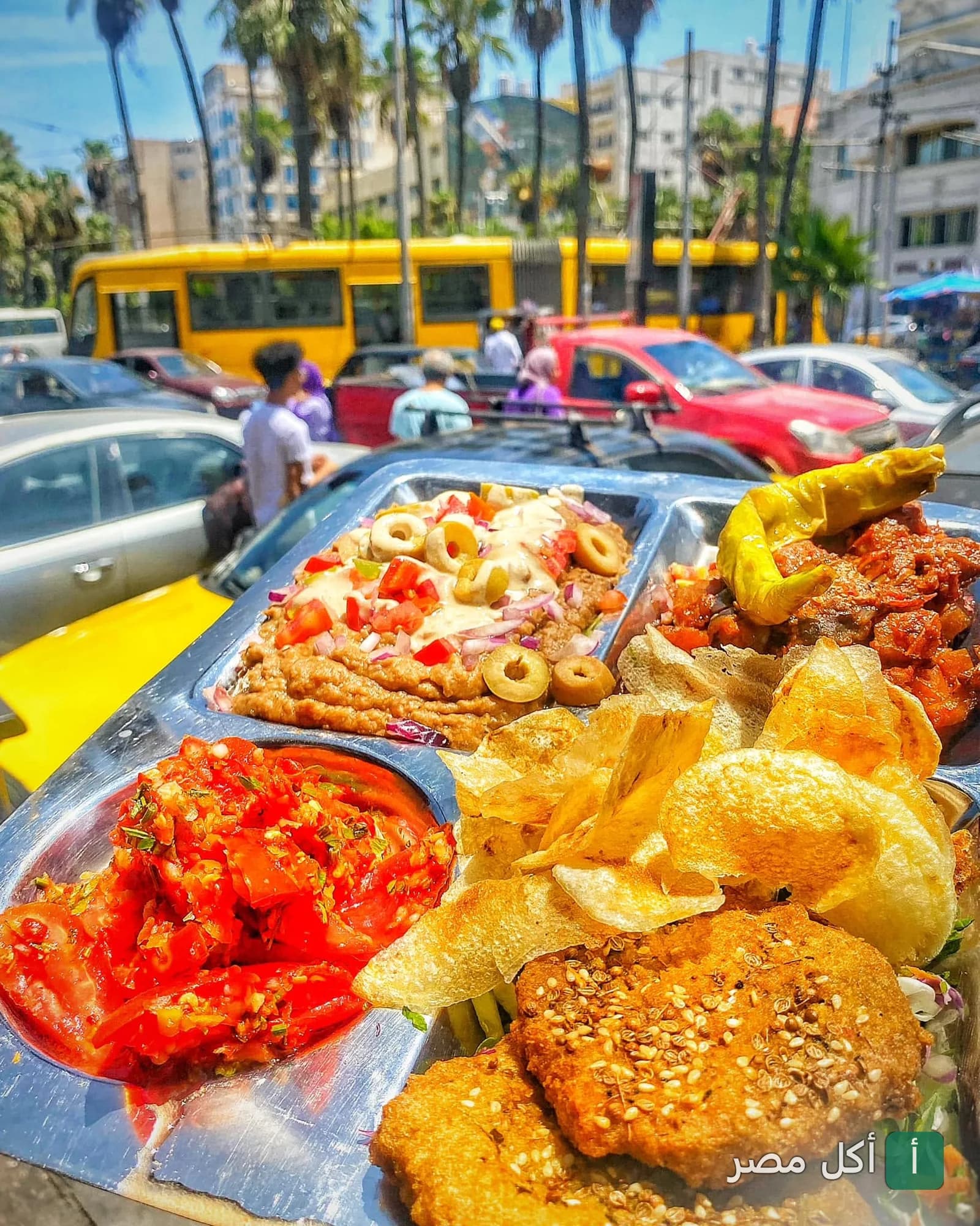 صينية إفطار شرقي من مطعم 16842 الشبراوي بمحطة الرمل، تحتوي على طعمية، فول، وسلطة في الهواء الطلق.
