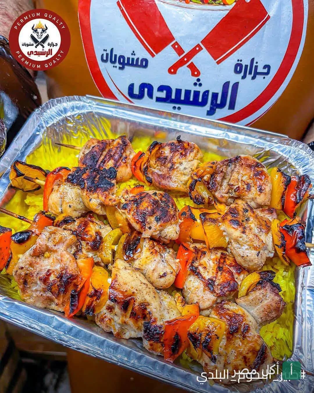 علبة ألومنيوم تحتوي على شيش طاووق مشوي مع فلفل ألوان وأرز أصفر من مشويات جزارة الرشيدي في مينا البصل.