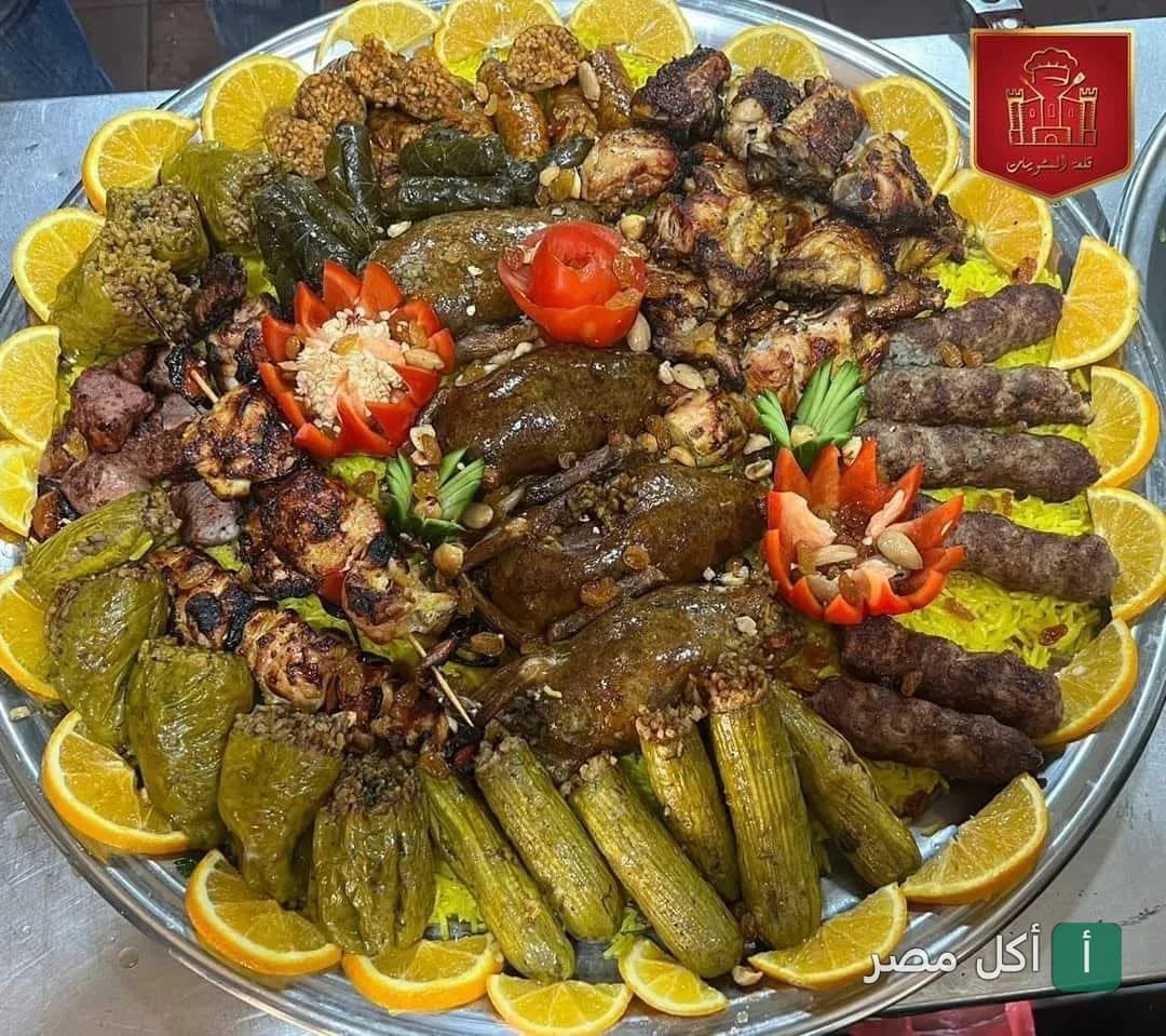 صينية مشويات مشكلة من مطعم قلعة المشويات بمينا البصل، تحتوي على كباب وكفتة وحمام ومحاشي مزينة بشرائح البرتقال.
