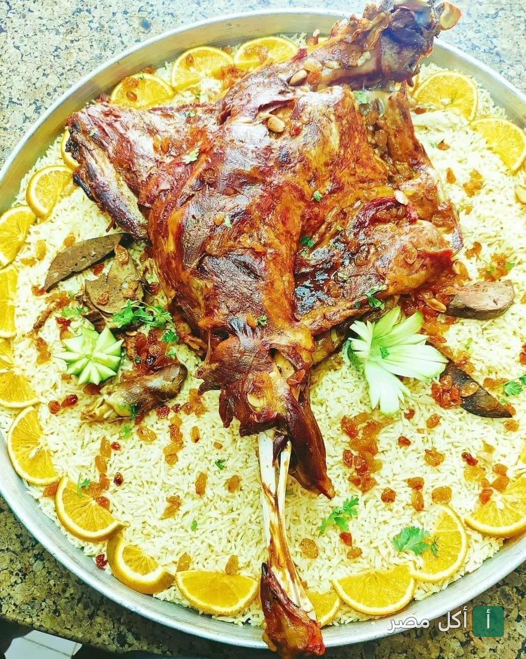 صينية كبيرة من لحم الضأن المشوي مع الأرز والمكسرات والزبيب مزينة بشرائح البرتقال في مطعم قلعة المشويات بالإسكندرية.