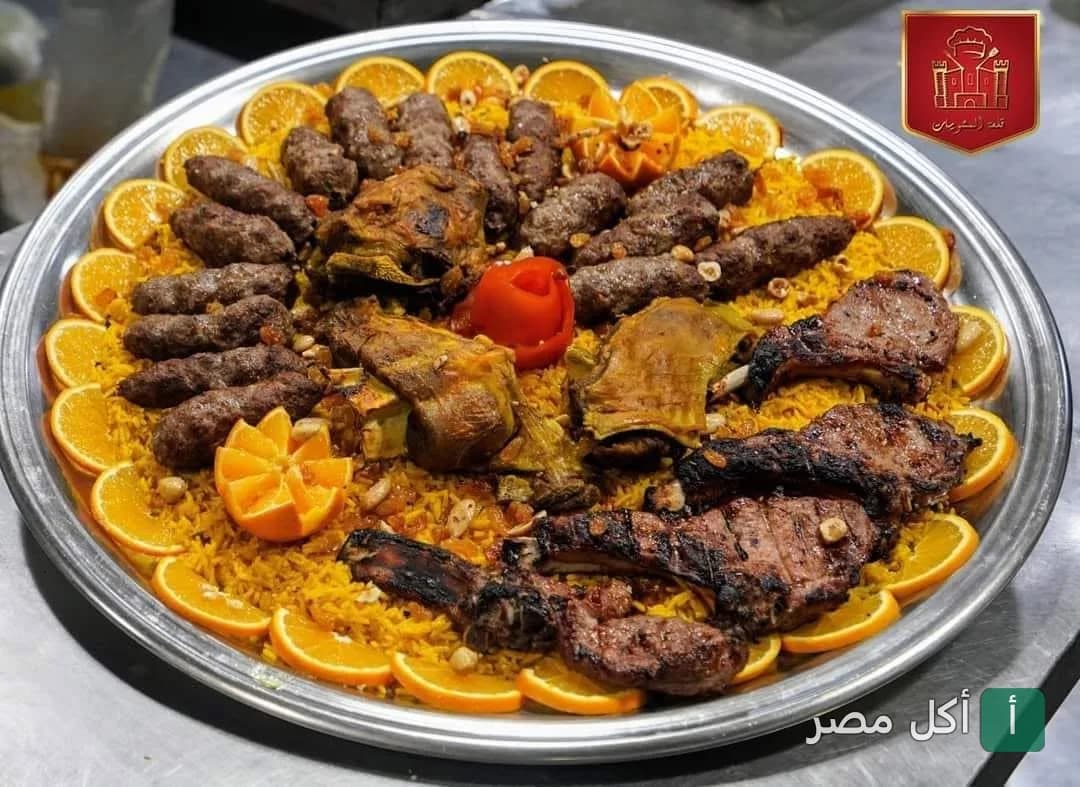 صينية مشاوي مشكلة من مطعم قلعة المشويات في مينا البصل بالإسكندرية، تضم كفتة وريش وأرز مزين بشرائح البرتقال.
