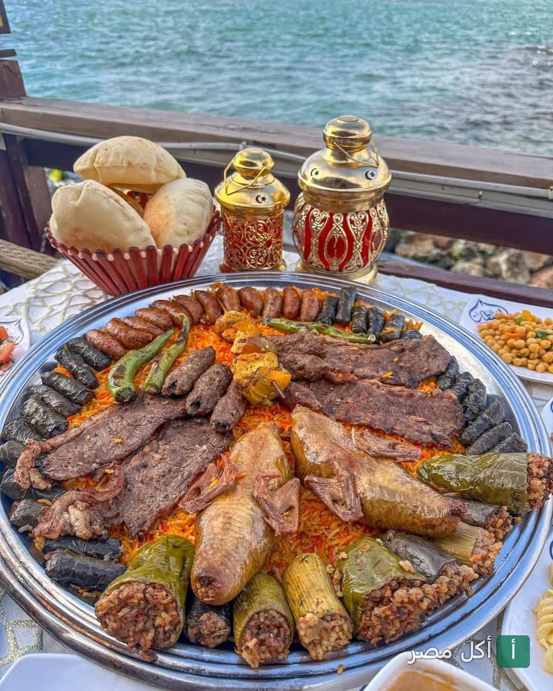 صينية مشويات ومحاشي متنوعة مع حمام محشي على طاولة مطلة على البحر في مطعم السلطان بالورديان.