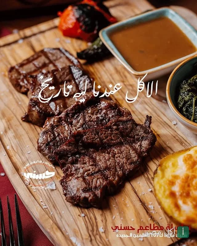 قطع ستيك مشوية على لوح خشبي مع صوصات في مطعم حسني بمينا البصل