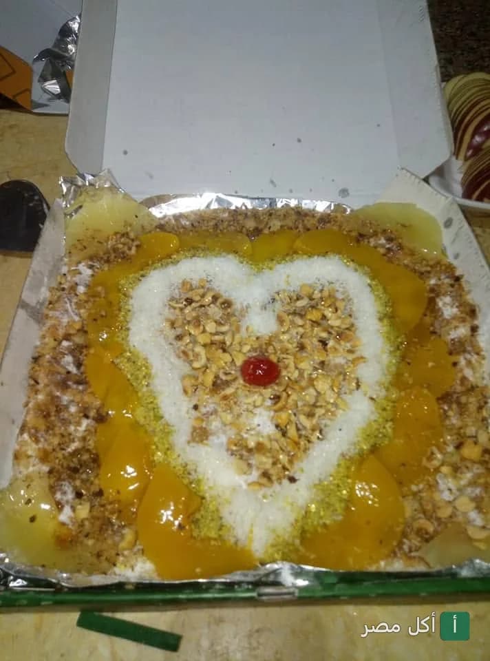 طبق حلوى مزين بقطع الخوخ وجوز الهند على شكل قلب في مطعم فطائر وبيتزا أبو مرزوق.