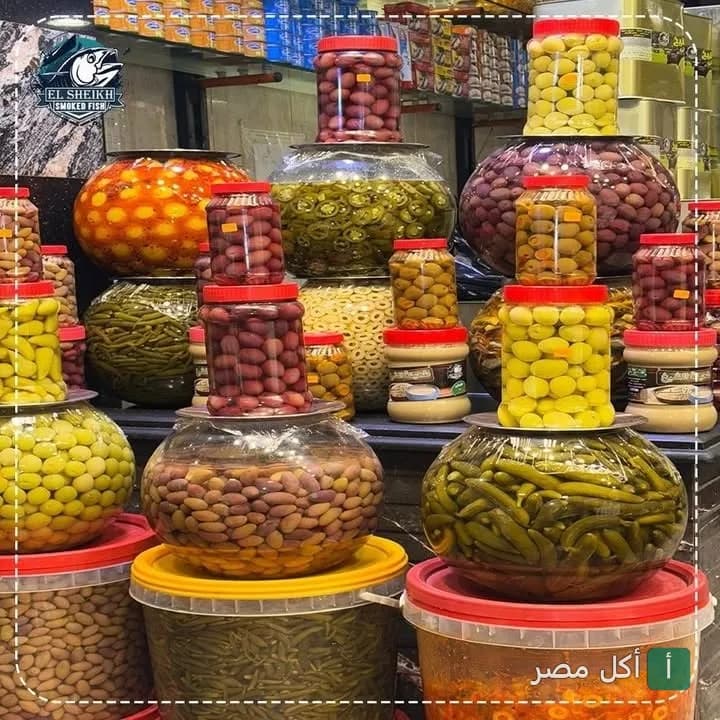 تشكيلة متنوعة من المخللات والزيتون في برطمانات زجاجية معروضة في محل الشيخ بمينا البصل.