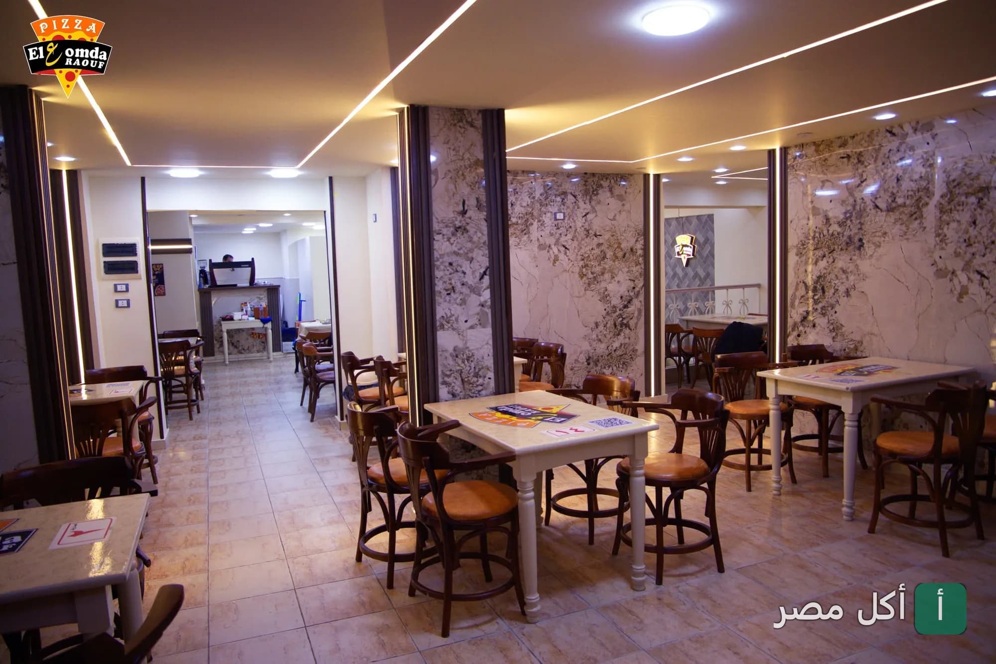 صالة مطعم العمدة في مينا البصل بالإسكندرية، تتميز بديكور عصري وطاولات خشبية.