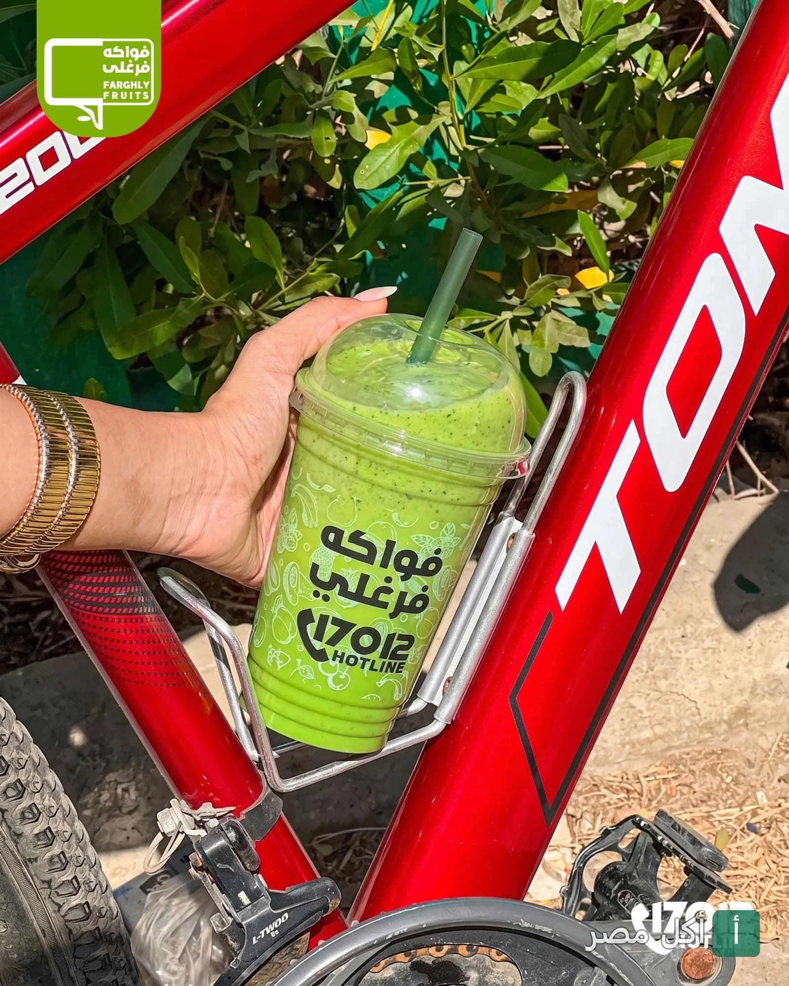 كوب عصير أخضر طازج من فواكه فرغلي في حامل دراجة حمراء.
