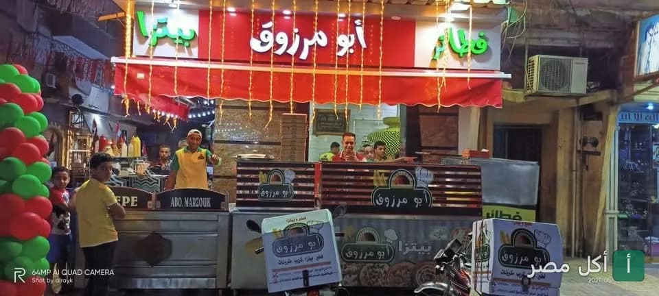 واجهة مطعم أولاد مرزوقة في مينا البصل، يظهر العمال أمام كاونتر التحضير مع لافتة مضيئة باسم المطعم.