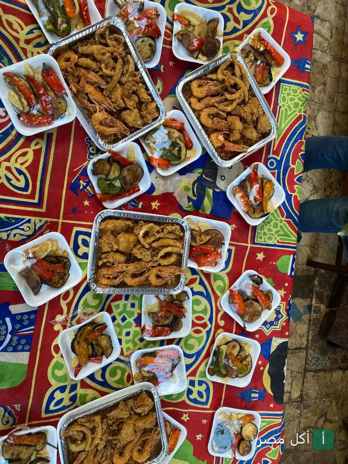 مائدة مليئة بأطباق الجمبري والسبيط المقلي مع الخضار المشوي في مطعم الاسكندراني بمينا البصل.