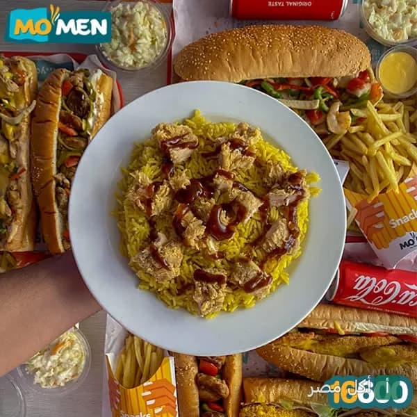 طبق أرز أصفر بقطع الدجاج وصوص في مطعم مؤمن بالورديان، محاط بساندوتشات وبطاطس مقلية.