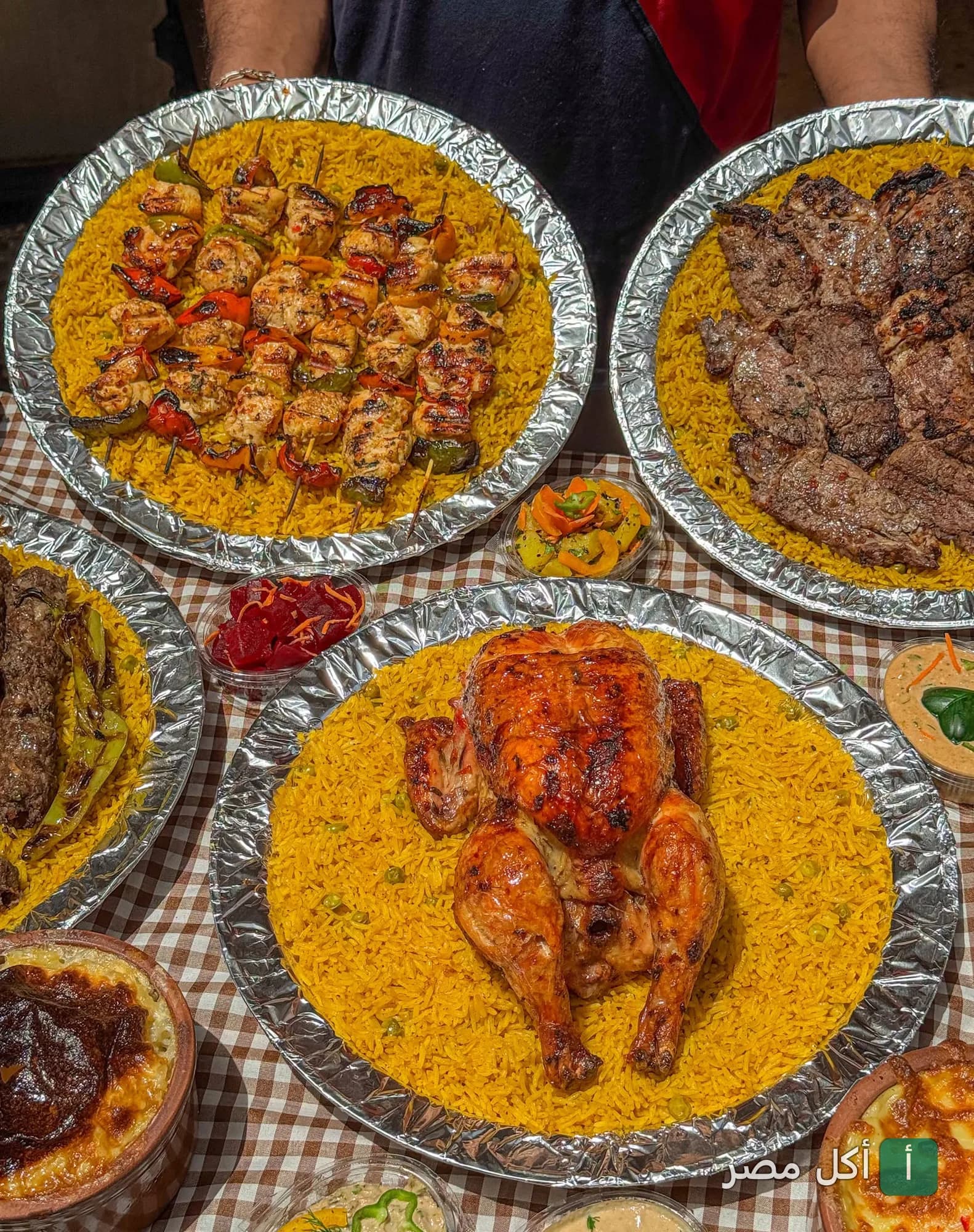 سفرة متنوعة من مطعم أبو سمية بسيدي بشر تضم أطباق مشويات دجاج ولحم مع أرز أصفر ومقبلات شرقية.